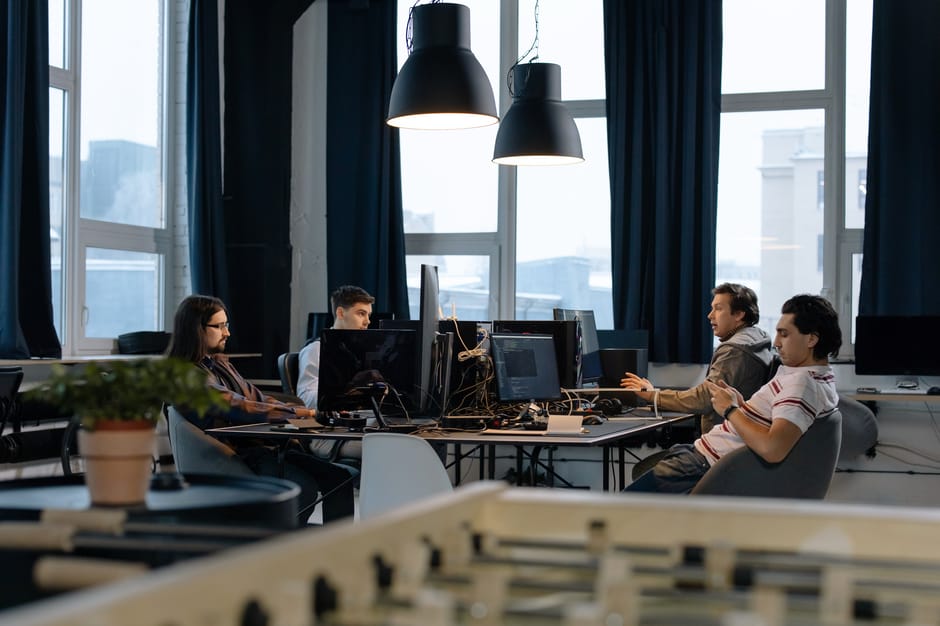 Workers collaborate in a modern office with computers, showcasing teamwork in technology development.
